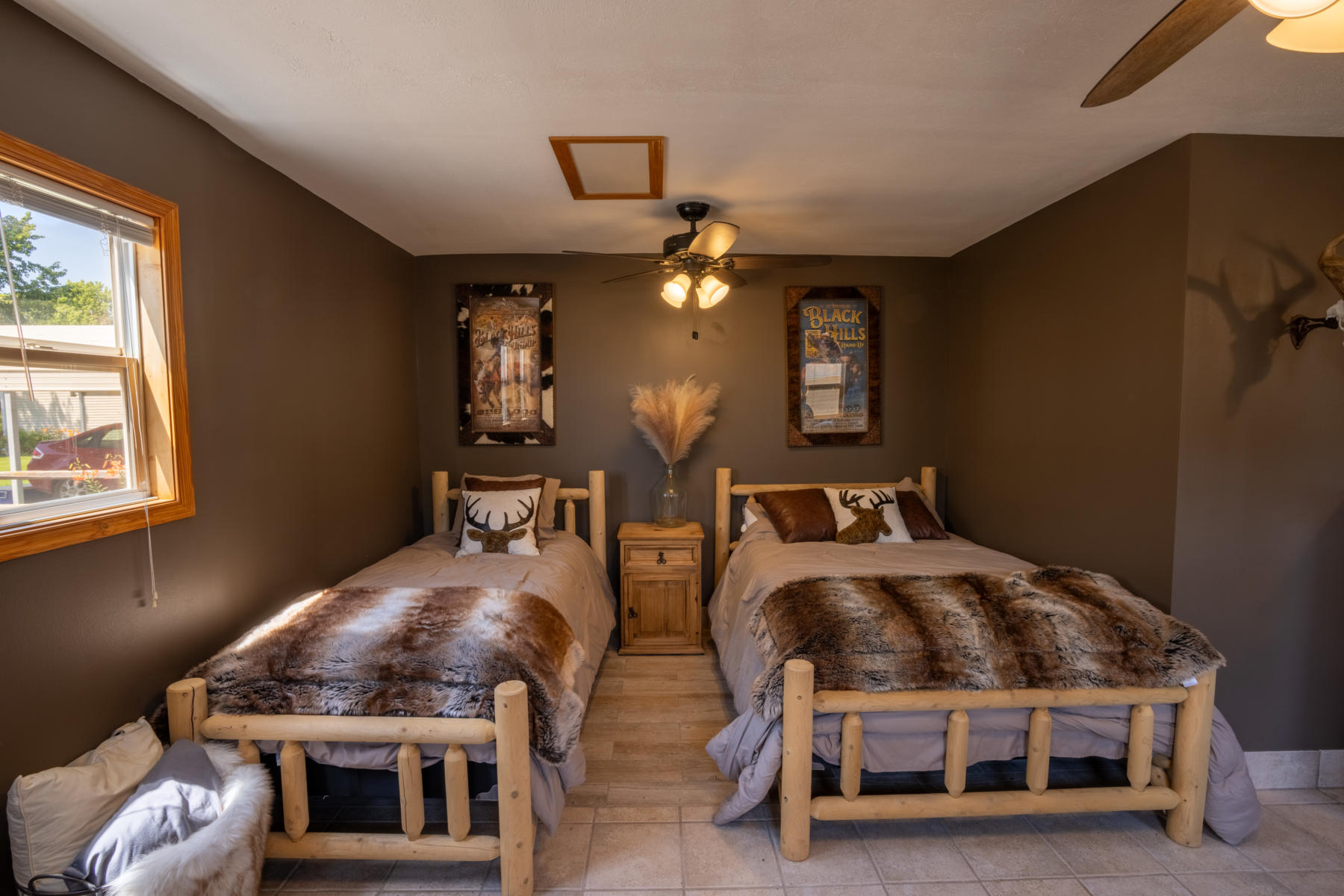 nebraska-waterfowl-hunting-lodge13 - Xtreme Waterfowlers - Nebraska Guided Duck & Goose Hunts Twin log-frame beds with deer-themed pillows and fur throws in a cozy cabin bedroom.